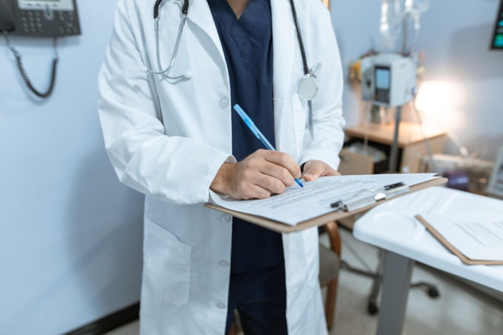 male locum tenens physician writing patient notes on a clipboard in medical office